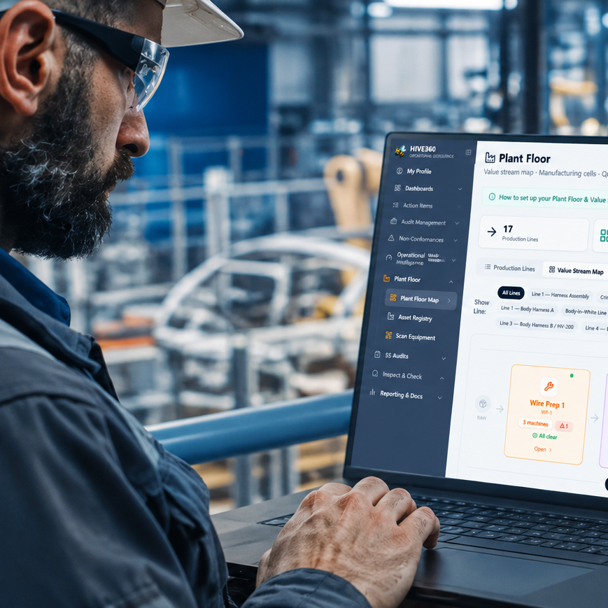 Internal Audit Software Worker in a hard hat using a laptop to monitor factory production data.