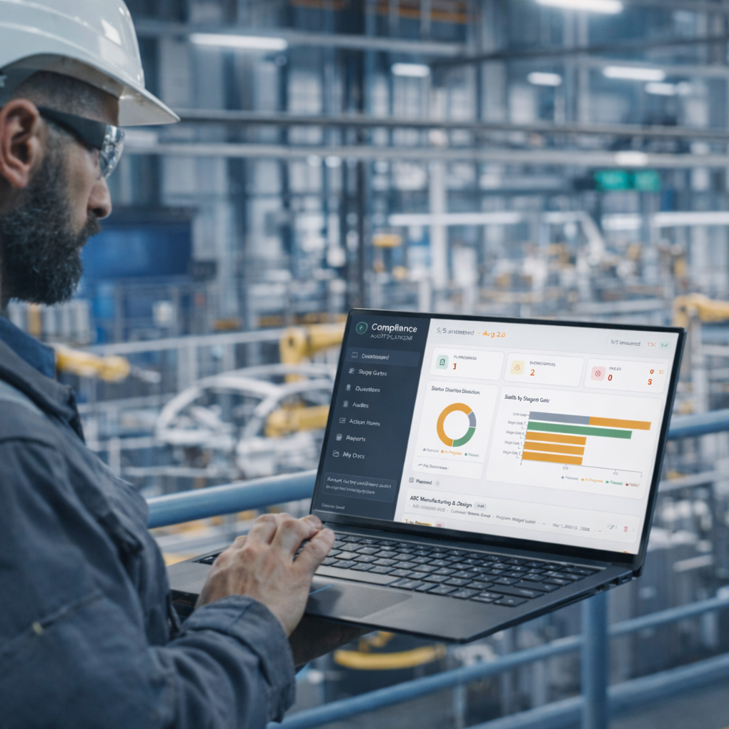 Worker in a hard hat using a laptop to monitor factory production data.